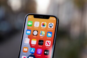 Hand holding an iPhone showing app icons