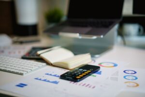 Desk with charts, calculator phone, and a notebook