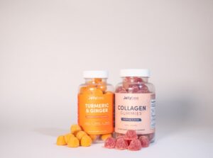 Two branded supplement gummy bottles with gummies on orange
