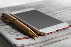 Phone and pen resting on a folded newspaper