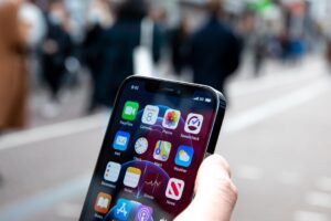 Hand holding an iPhone on a crowded street