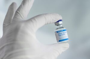 White-gloved hand holding a small medication vial