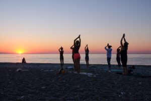 Group doing yoga on a beach at sunset