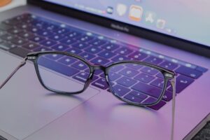 Reading glasses on a laptop keyboard in purple light