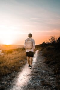 Man walking a dirt path at sunset