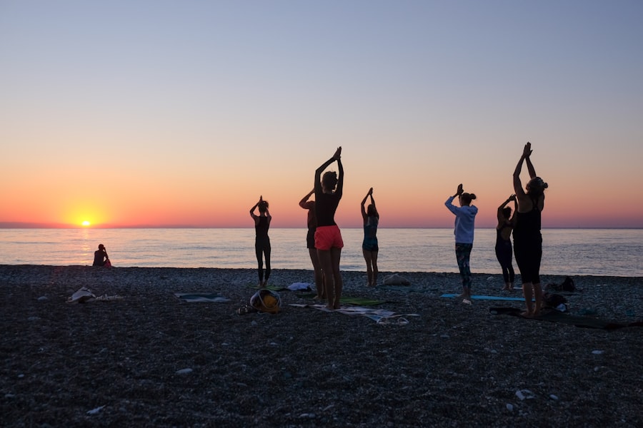 Group practicing yoga on a beach at sunset